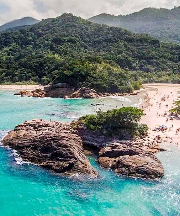 Beach with rocky formations and lush green mountains in the background.