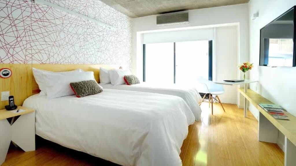 Modern hotel room with a large bed and bright decor.