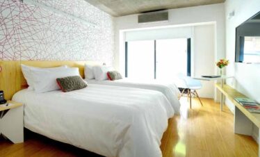 Modern hotel room with a large bed and bright decor.
