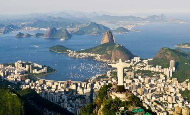Panoramic view of Rio de Janeiro featuring iconic landmarks and lush green surroundings.