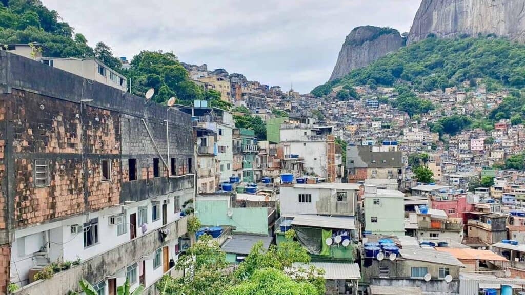 Favela community in Rio de Janeiro with hillside houses and lush green mountains in the background.