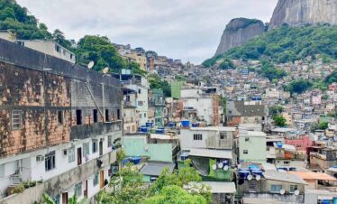 Favela community in Rio de Janeiro with hillside houses and lush green mountains in the background.