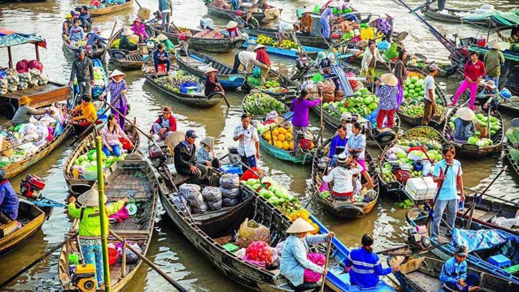 Colourful boats at a lively floating market with vendors selling fresh produce.