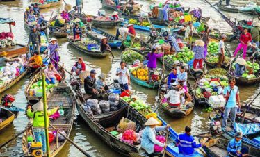 Colourful boats at a lively floating market with vendors selling fresh produce.