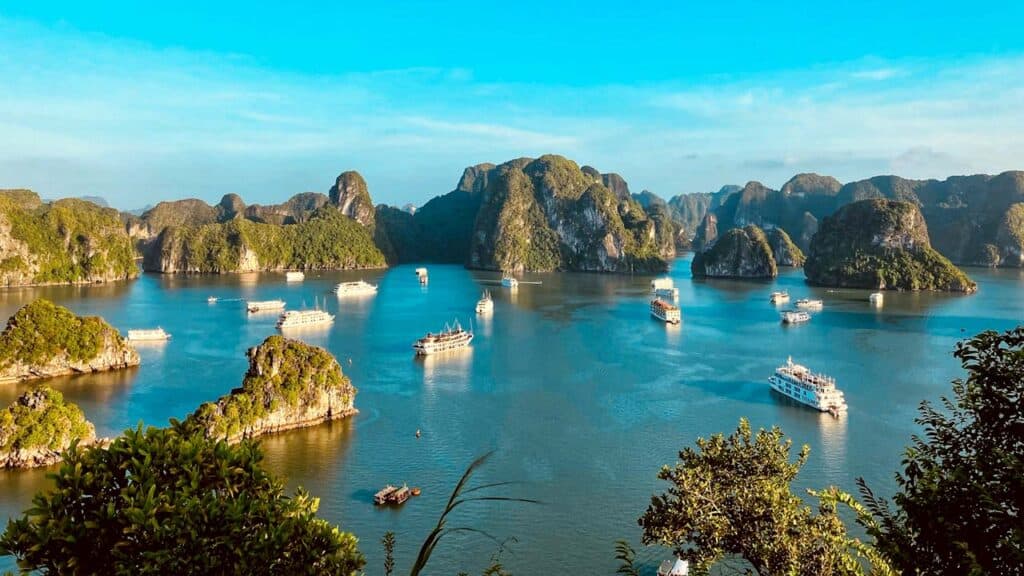 Scenic tropical bay with limestone islands and boats in clear blue water.