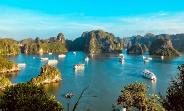 Scenic tropical bay with limestone islands and boats in clear blue water.