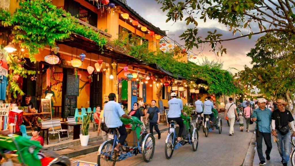 Lively street with cyclists and pedestrians in a colourful town setting.