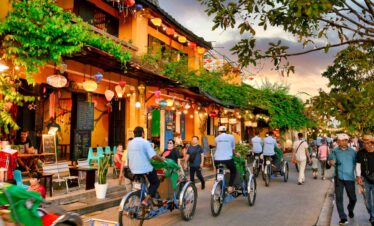 Lively street with cyclists and pedestrians in a colourful town setting.