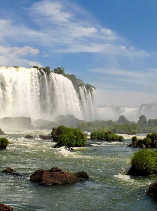 Waterfalls at Iguazu Falls, Argentina, with lush greenery and blue sky.