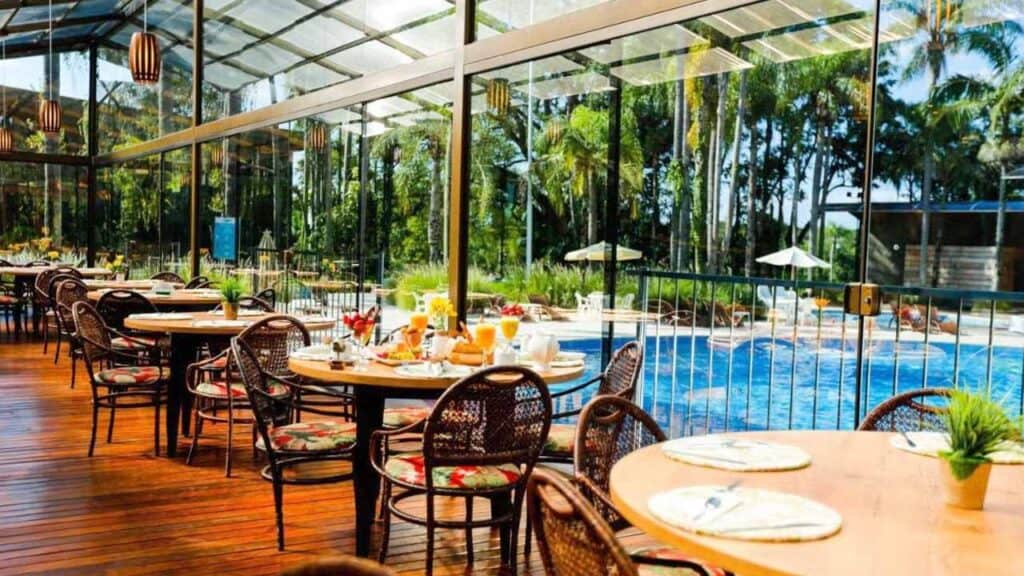 Indoor tropical dining area with pool view and wicker chairs.