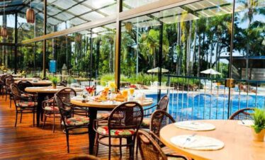 Indoor tropical dining area with pool view and wicker chairs.
