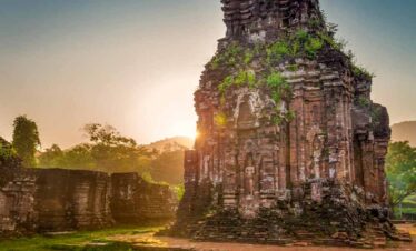 Ancient stone temple with lush greenery at sunset, showcasing historical architecture and serene nat.