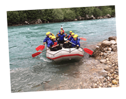 Group of people white water rafting on a river with safety gear.