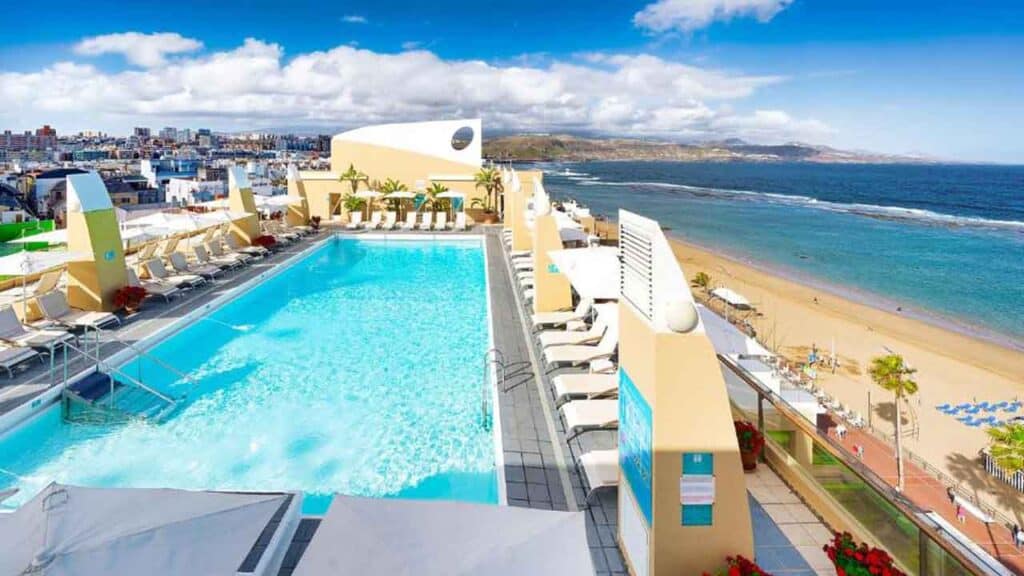 Beachside pool with sun loungers and umbrellas at Travel Buddies Holidays resort.