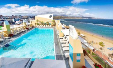 Beachside pool with sun loungers and umbrellas at Travel Buddies Holidays resort.