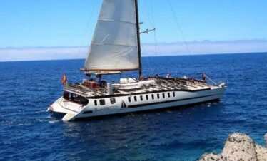 A luxury sailing yacht cruising on the open sea under a clear blue sky.