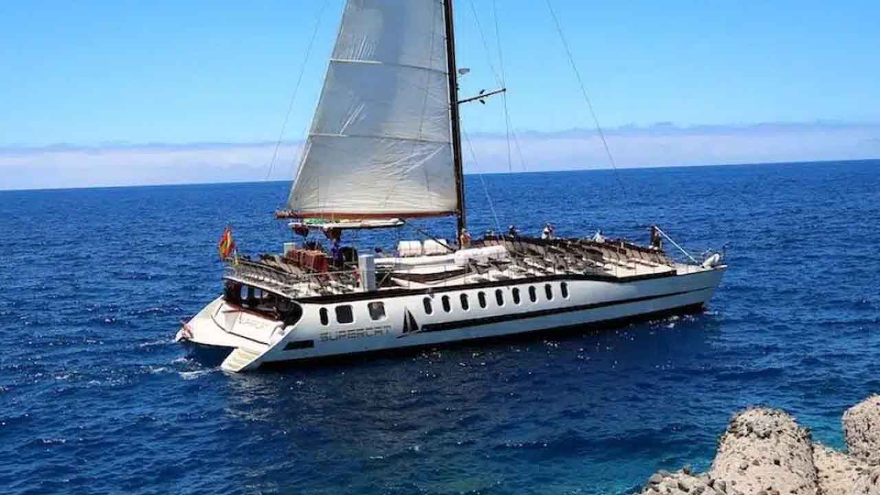 A luxury sailing yacht cruising on the open sea under a clear blue sky.