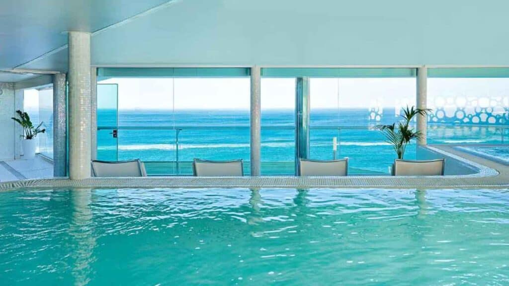 Indoor pool overlooking the ocean with large windows and a scenic sea view.