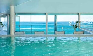 Indoor pool overlooking the ocean with large windows and a scenic sea view.