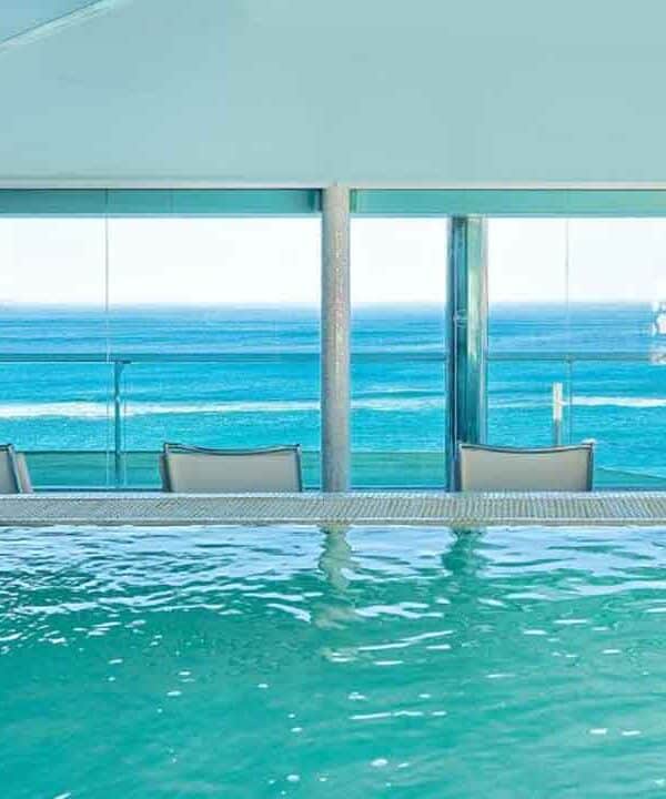 Indoor pool overlooking the ocean with large windows and a scenic sea view.