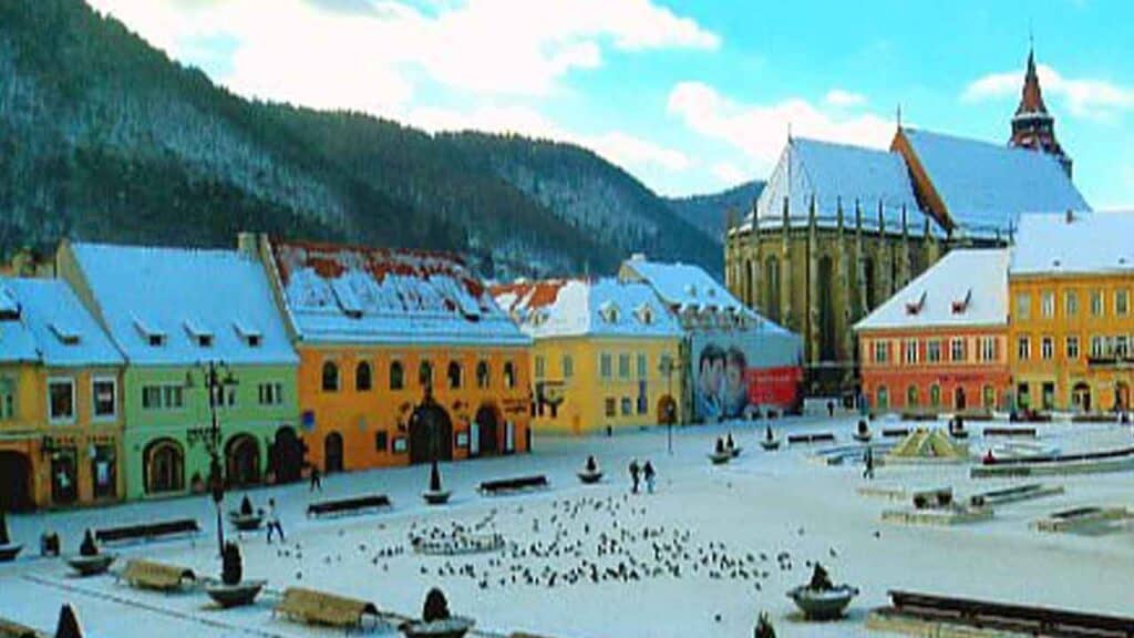 Covered town square with historic architecture and mountain scenery.