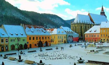 Covered town square with historic architecture and mountain scenery.