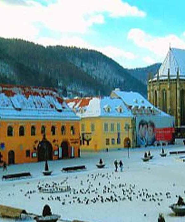 Covered town square with historic architecture and mountain scenery.
