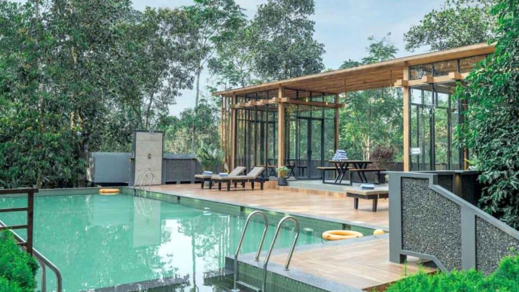Outdoor pool with a stylish glass pavilion surrounded by trees and nature.