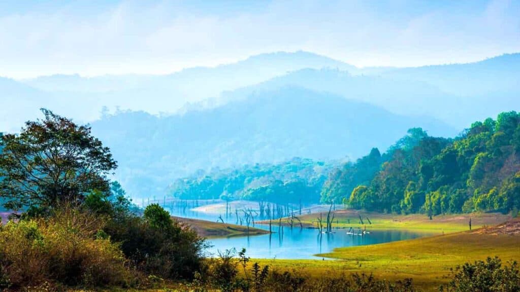 Beautiful mountain lake surrounded by greenery and misty hills in the background.