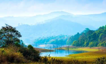 Beautiful mountain lake surrounded by greenery and misty hills in the background.