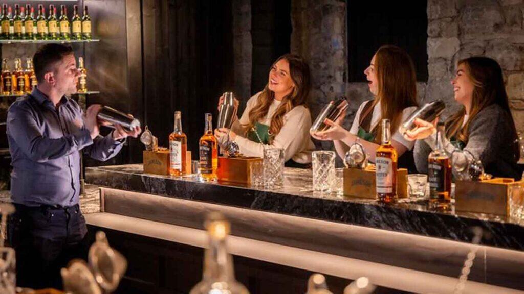 Group of women enjoying cocktails at a bar with a bartender serving drinks.