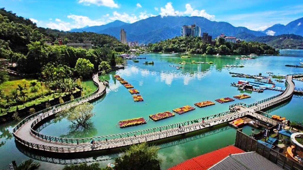 Scenic view of a river in Taiwan with mountains and cityscape in the background.
