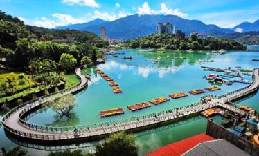 Scenic view of a river in Taiwan with mountains and cityscape in the background.