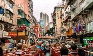 Hong Kong city tour with tourists exploring busy streets and high-rise buildings.