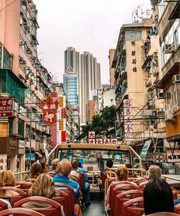 Hong Kong city tour with tourists exploring busy streets and high-rise buildings.