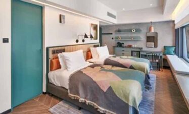 Stylish hotel room featuring two beds, colourful bedding, and contemporary decor for a comfortable s.
