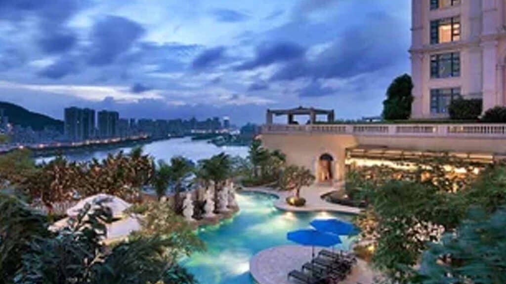 Rooftop pool overlooking city skyline during evening twilight.