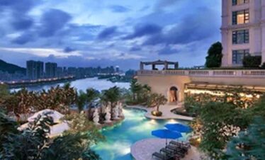 Rooftop pool overlooking city skyline during evening twilight.
