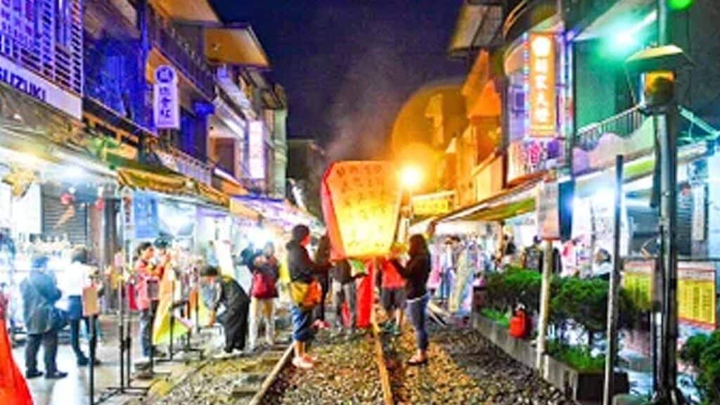 Vibrant night market with colourful lights and busy shoppers exploring stalls.