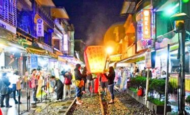 Vibrant night market with colourful lights and busy shoppers exploring stalls.