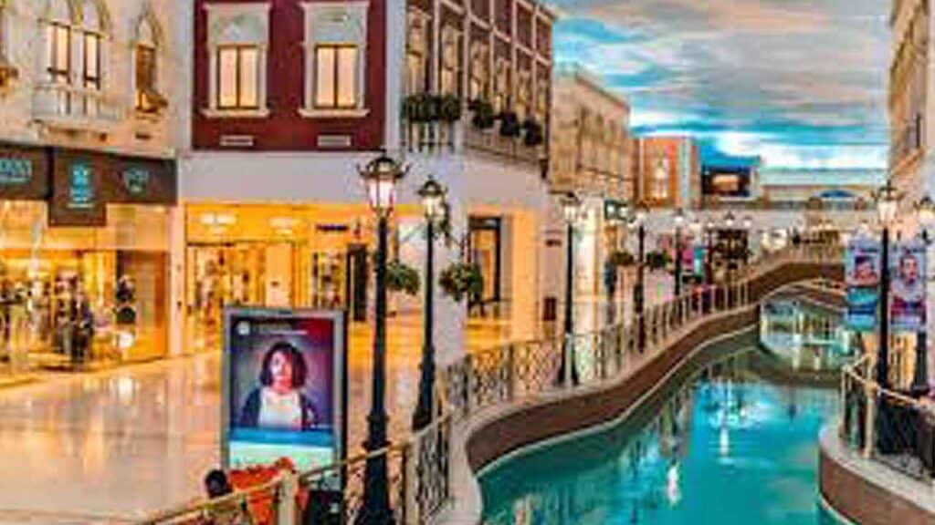 Vibrant shopping district with colorful storefronts and canal in a lively city setting.