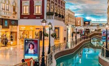 Vibrant shopping district with colorful storefronts and canal in a lively city setting.