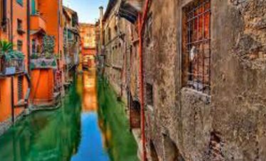 Vibrant colourful buildings lining a canal in Venice, Italy, with reflections in the water.