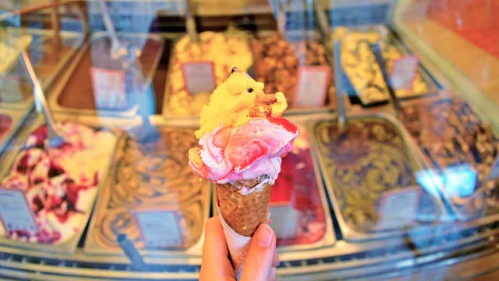 Ice cream cone with colourful scoops and toppings in a gelato shop.