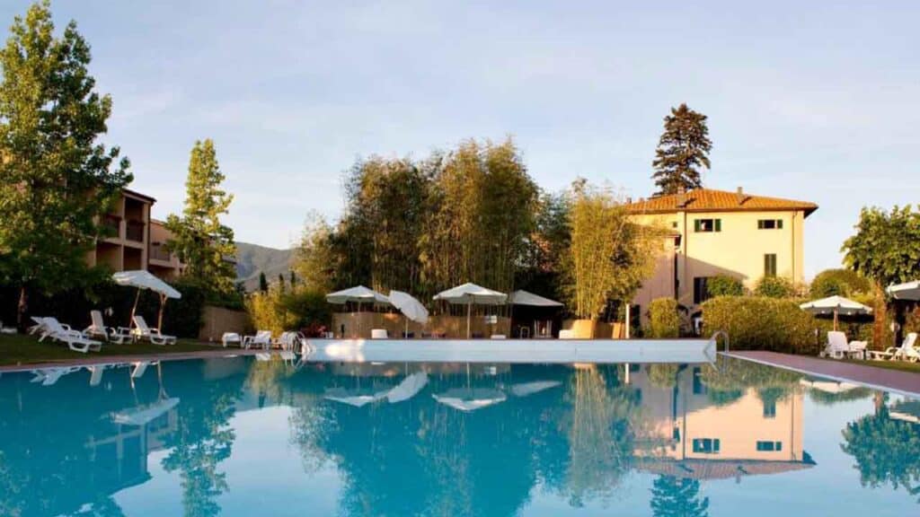 Serene outdoor pool surrounded by sun loungers and umbrellas, set in a picturesque countryside locat.