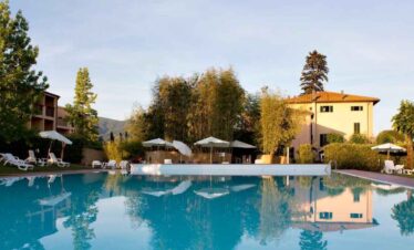 Serene outdoor pool surrounded by sun loungers and umbrellas, set in a picturesque countryside locat.