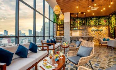 Cozy lounge area with large windows overlooking the city skyline, stylish furniture, and warm lighti.