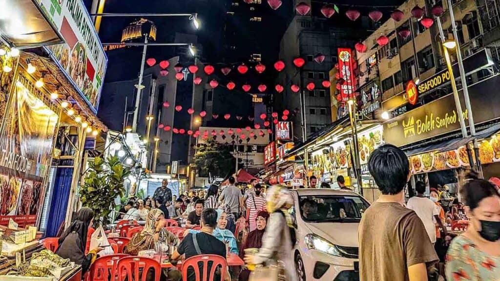 Vibrant night market with food stalls, lanterns, and busy crowds in an Asian city.