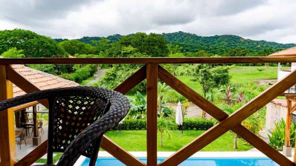 Balcony overlooking lush green fields and rolling hills under a cloudy sky.