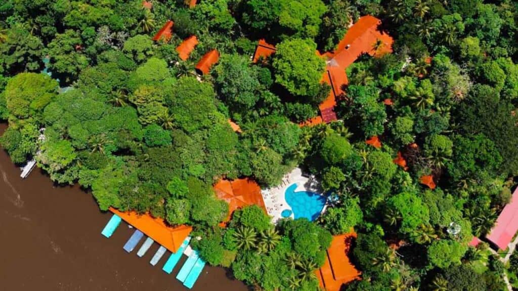 Aerial view of a tropical resort with orange-roofed buildings amid lush green trees.